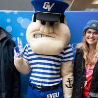 Two alumni pose with Louie at the Detroit Red Wings GVSU Night